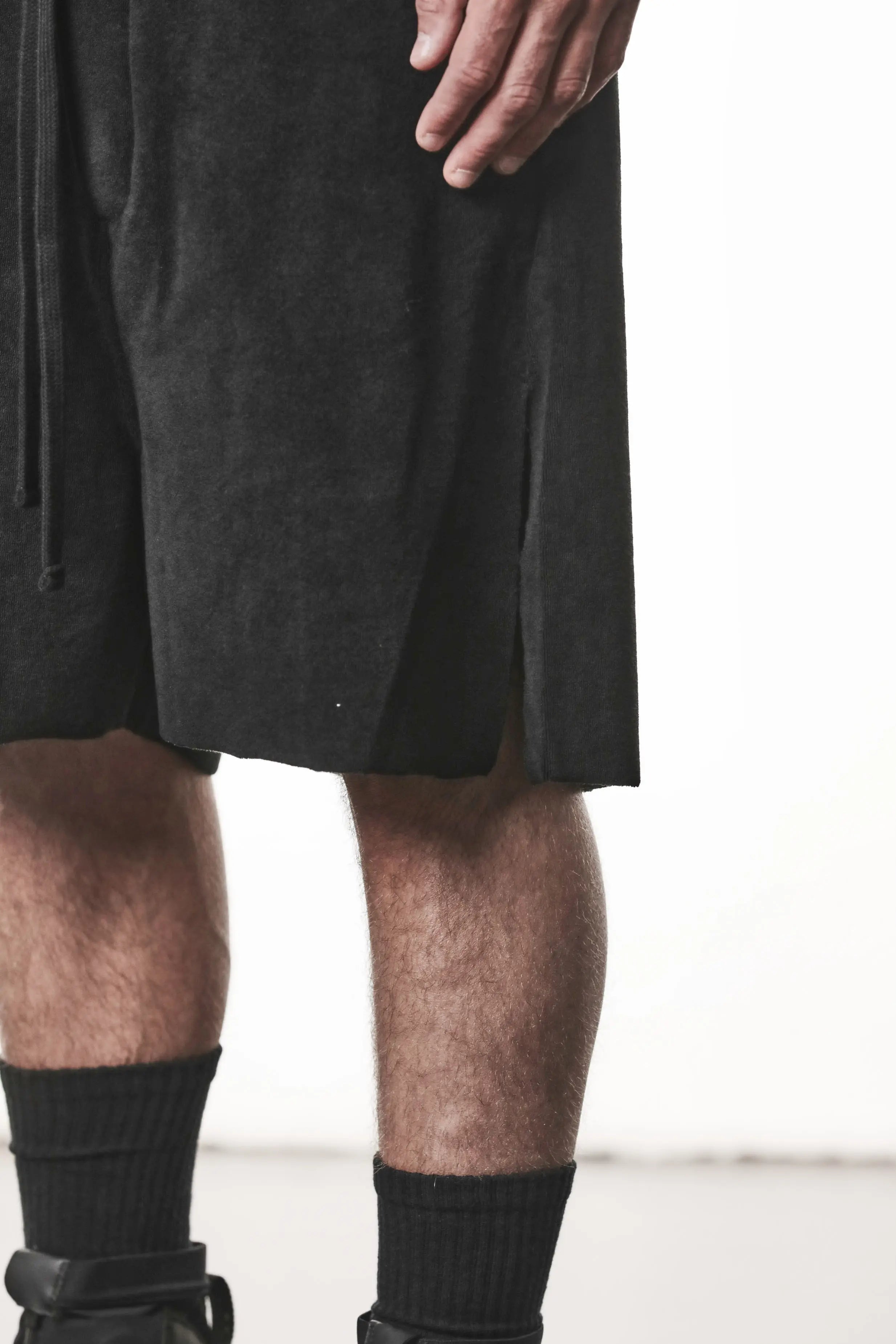 Thom Krom, Mens Shorts, Black, Elasticated Waistband, Drawstring, Raw cut hem and slits, Cotton Terry, Woven Inserts, 1/2 Legs, Side Pockets, Leg Fit Close-up 3/4 View. 