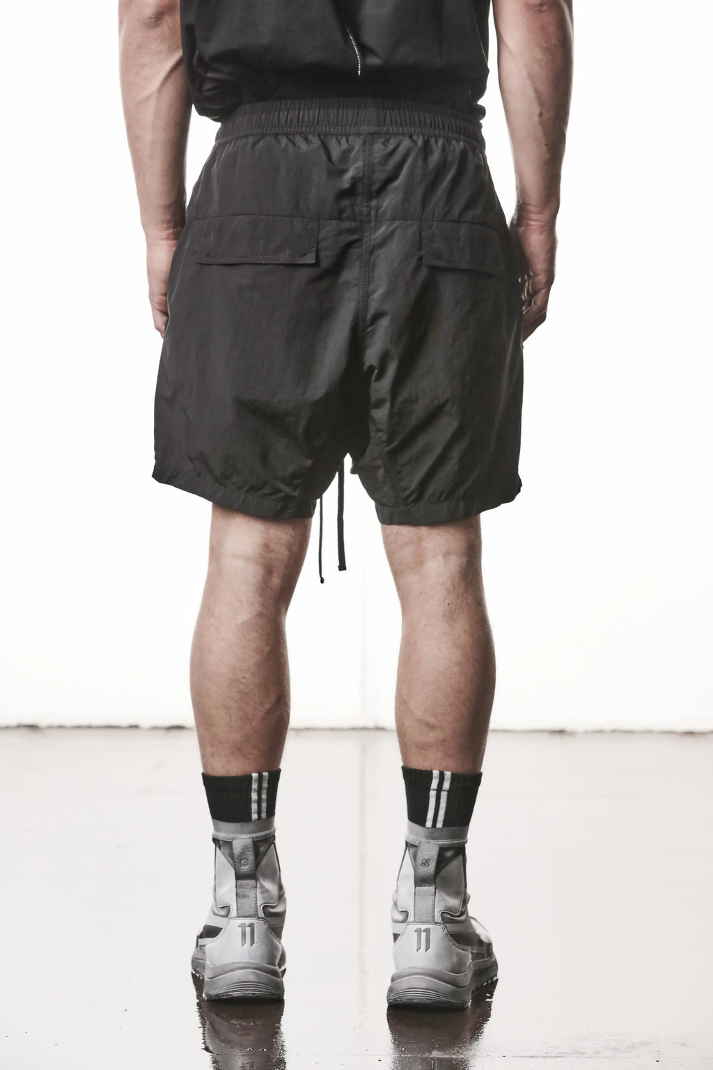 Thom Krom, Mens Shorts, Black, Polyamide, Side Pockets, Elasticated Waistband, Drawsting, Cross Seams, Wide Fit, Over the Knee Legs, Drop-Crotch, Hidden Zip Pockets, Back View. 