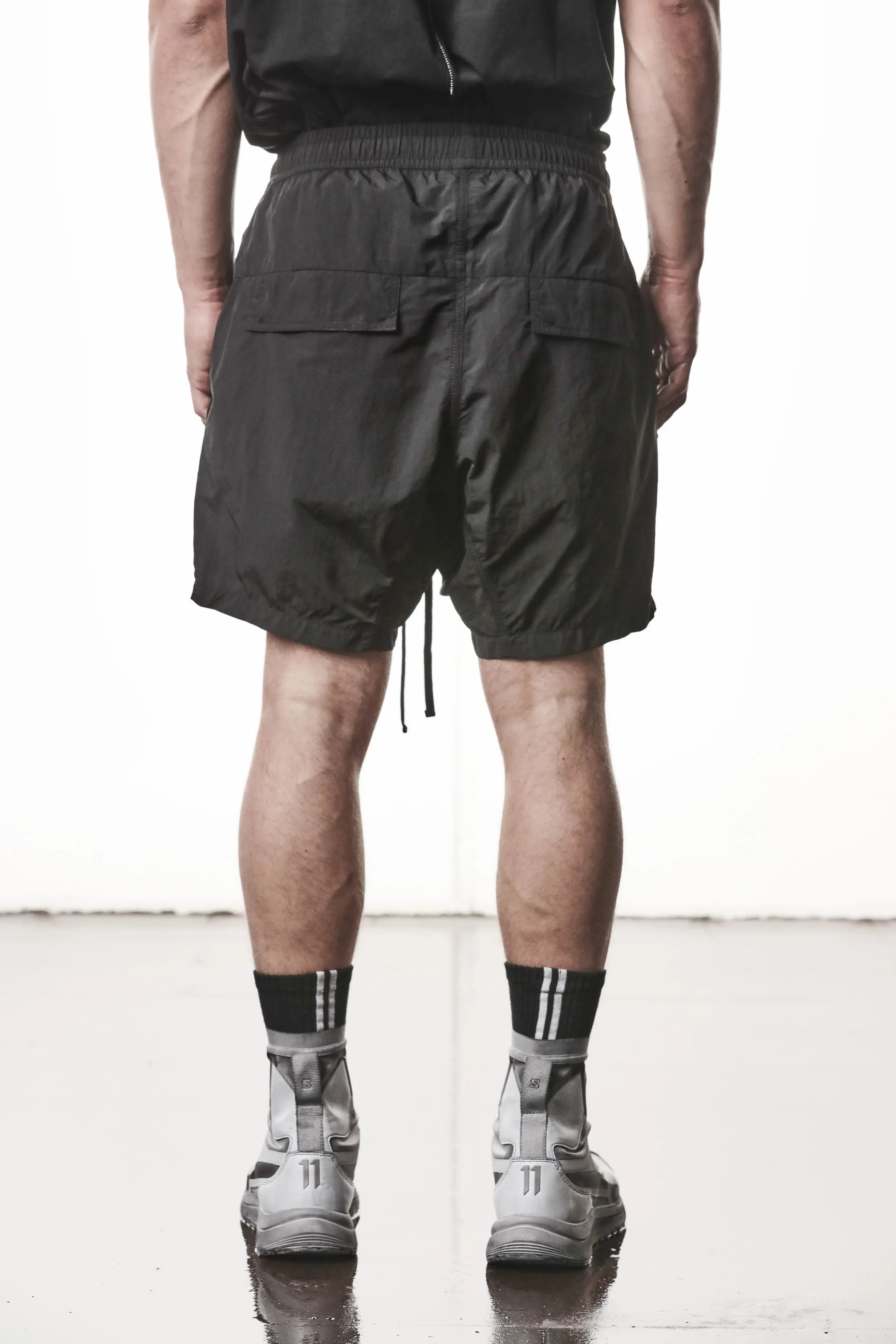 Thom Krom, Mens Shorts, Black, Polyamide, Side Pockets, Elasticated Waistband, Drawsting, Cross Seams, Wide Fit, Over the Knee Legs, Drop-Crotch, Hidden Zip Pockets, Back View. 