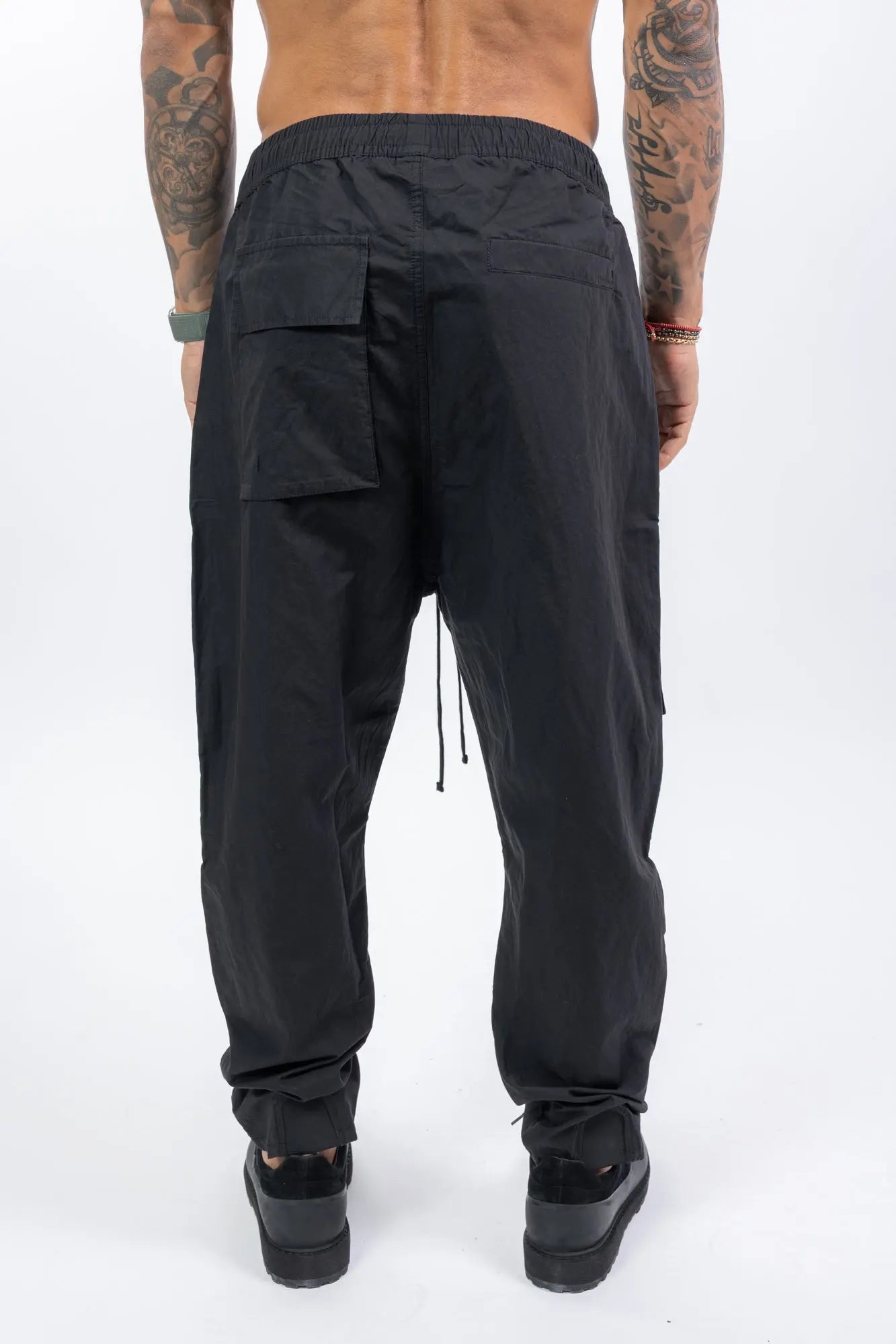Thom Krom,Mens Trousers,Relaxed Fit,Mid-Rise Waist,Drop Crotch,Tapered Leg,Elastic Waistband With Adjustable Drawstring,Concealed Button Placket With Logo Buttons At The Front,Two Patch Bellows Pockets With Zipper On The Front,Two Patch Bellow pockets With Flaps On The Front,Welt Pocket 
And Patch Bellows Pocket With Flap On The Back,Security Pocket With Zipper On The Inside,Leg Hem With Elastic Insert On The Back, Back View.