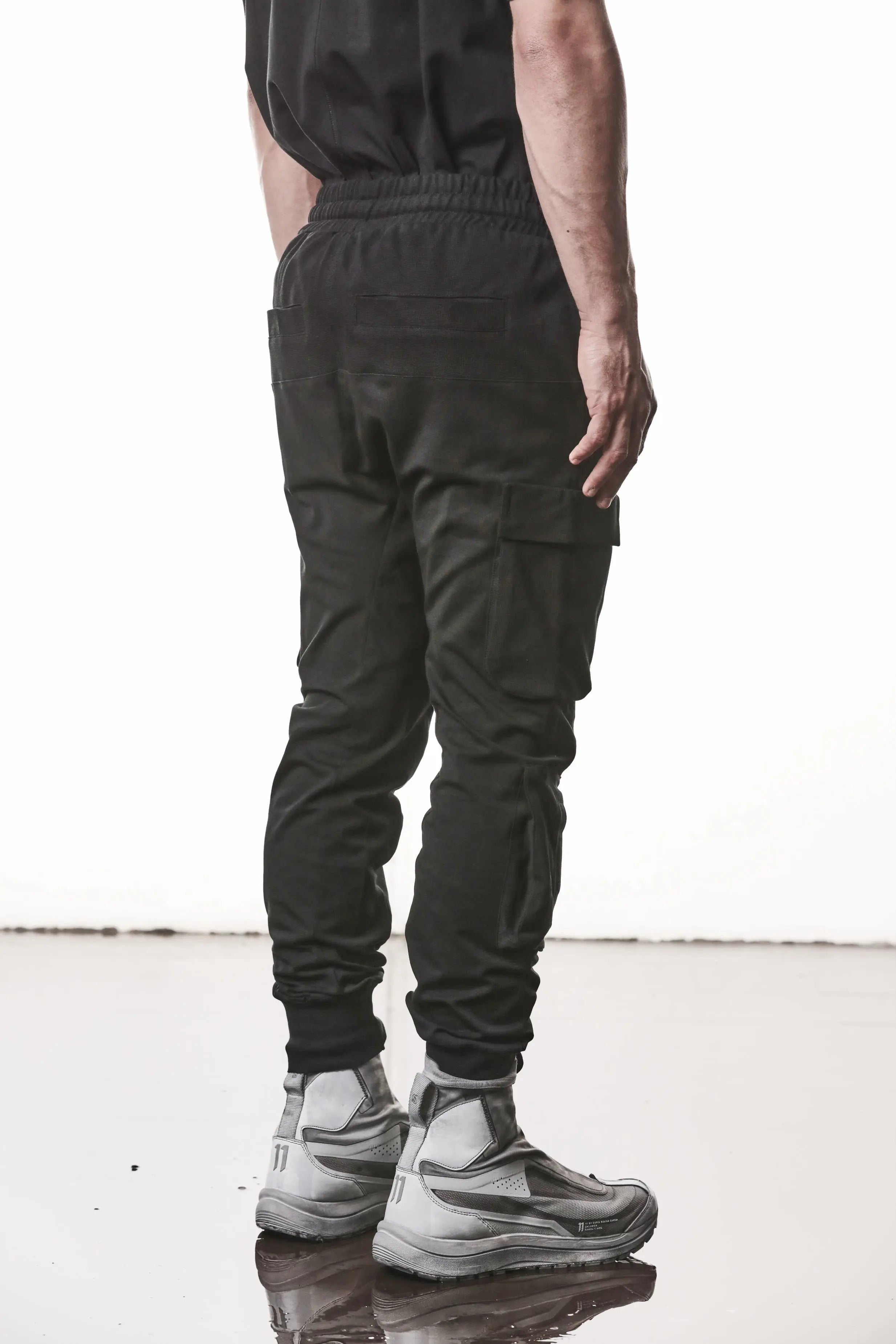 Thom Krom, Mens Pants, Black, Cargo Pockets, Stretch Cotton, Elastane, Spandex, Elasticated Waistband, Drawstring, Elasticated Cuffs, Long Legs, Regular Fit, Side Pockets, YKK Zippers, Back Portrait 3/4 View. 