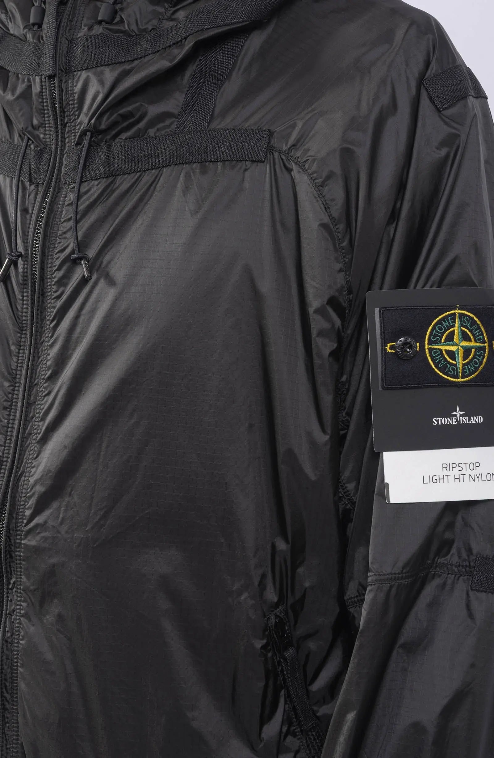 Stone Island, Mens Jacket, Windbreaker, Black V0029, Semi-Transparent, Elasticated Cuffs, Full Zip, YKK Zippers, Compass Badge, Logo-Patch, Side Pockets, Hooded, Badge Close-up. 