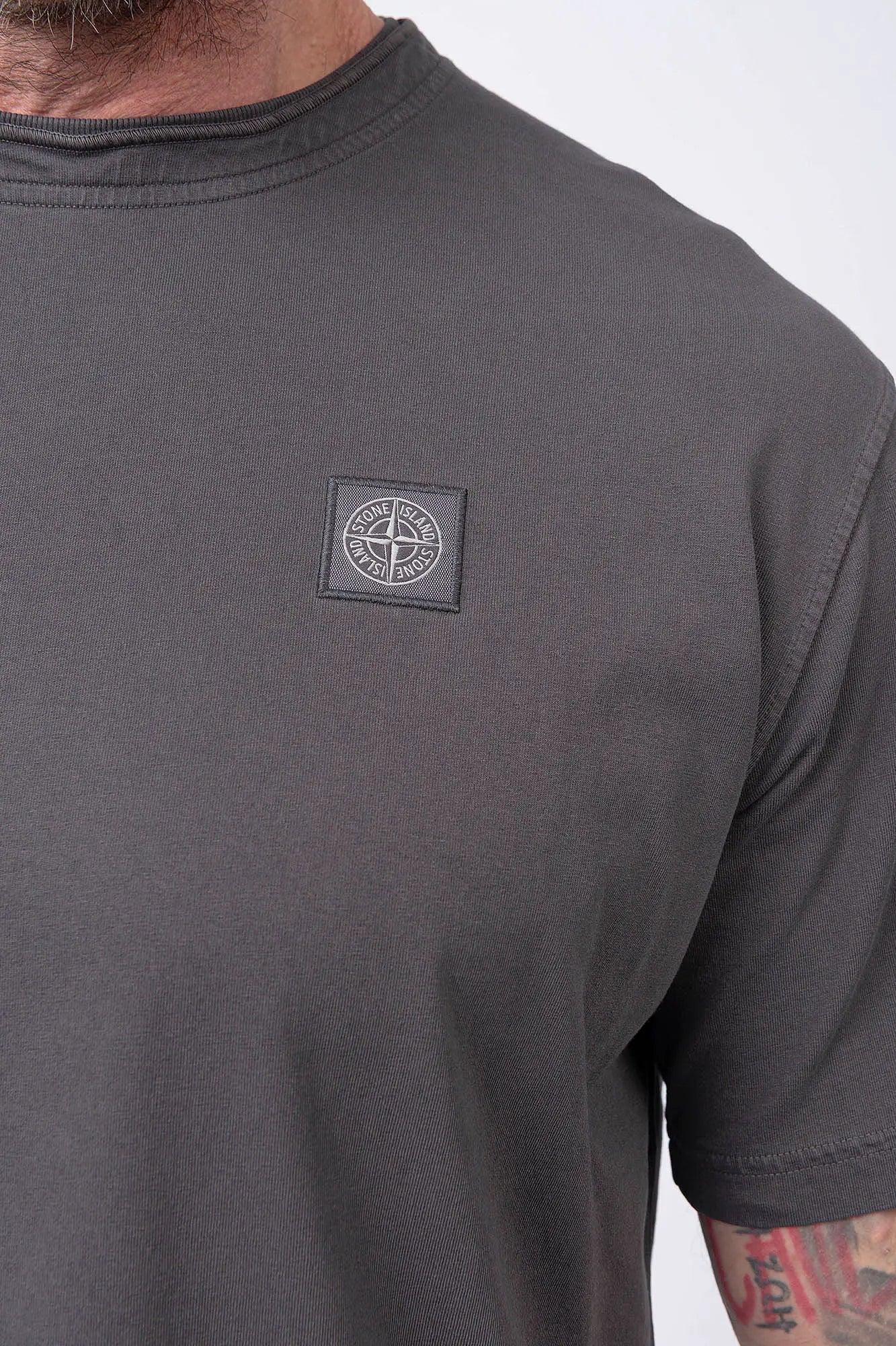Stone Island, Mens T-Shirt, Charcoal V0165, Grey, Gray, Garment Dyed, Short Sleeves, Elastic Ribbing, Organic Cotton, Wide Fit, Raw-cut Neck, Crewneck, Round Neck, Compass Badge, Logo-patch, Chest Compass Patch, Compass Patch Close-up View. 